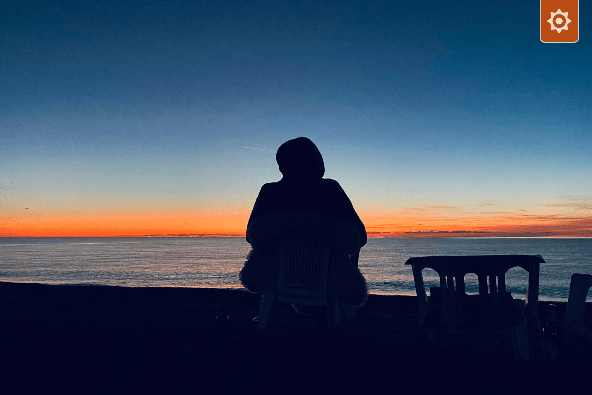 Eine Person sitzt in der Dämmerung auf einem Stuhl und blickt auf eine ruhige Meeresoberfläche – ein Symbol für die "Ruhe des Boards" und die Schaffung von Klarheit durch disziplinierte Beobachtung.